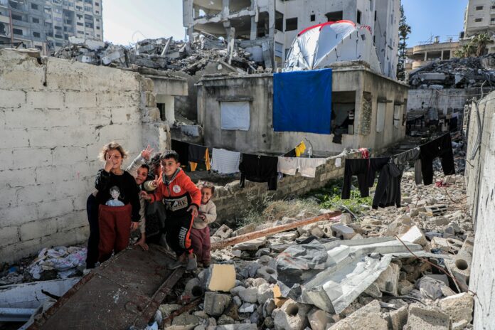 Photo by Mohammed Ibrahim A group of people standing next to a pile of rubble