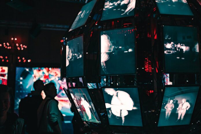 Photo by Maxim Hopman a group of people standing around a display of video screens