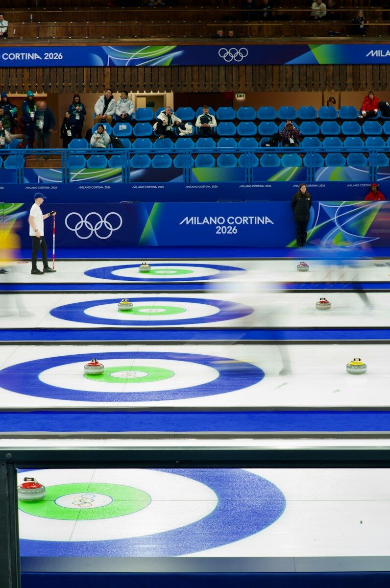 Curling match with athletes sliding stones on ice